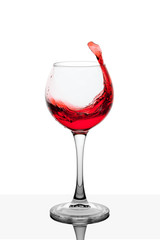 Splash of red wine in the cup filling on a white background