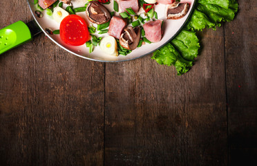 Raw meat in dish and frying pan, spices, knife on wooden table, vegetables, top view