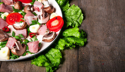 Raw meat in dish and frying pan, spices, knife on wooden table, vegetables, top view