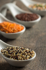 White spoons on wood with quinoa and lentils and barley