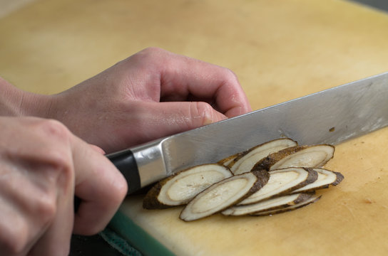 Chef working cutting root vegetable on cuttingboard