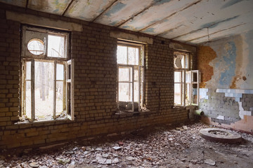 Abandoned large hall with big windows and debris on the floor