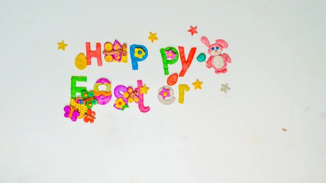 Children make holiday inscription from plasticine and confetti "Happy Easter", a motion stop
