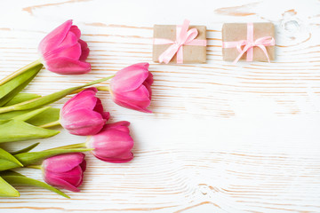 Букет розовых тюльпанов и упакованные подарки на белом деревянном фоне - obrazy, fototapety, plakaty