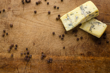 black round pepper and cheese on wooden board © VlaDee