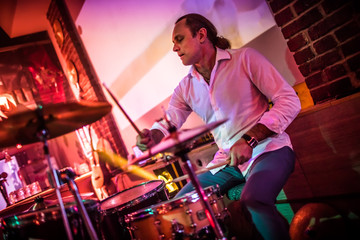 Drummer playing on drum set on stage.