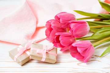 Подарки и букет розовых тюльпанов на столе
