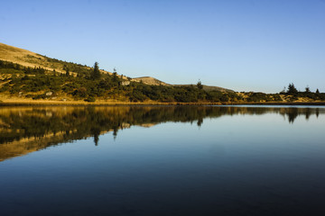 reflection of  hill and forest in lake in Carphatian mountains Ukraine in autumn clear sky at sunrise