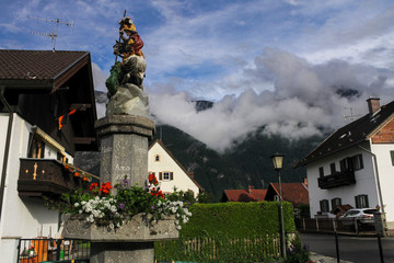 fog over mountains in small Bavaria village Oberau street travel Germany Alps summer fountain 