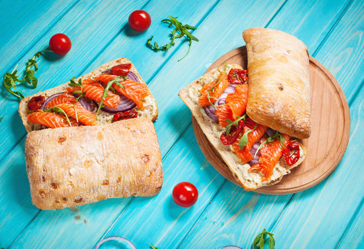sandwich with smoked salmon on blue wooden table.
