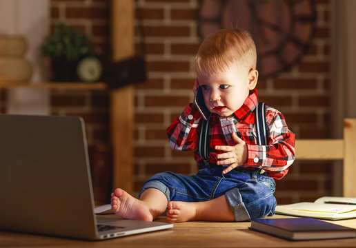 concept of baby boy working on computer and talking on phone