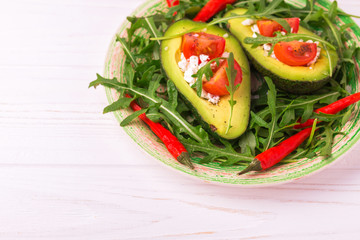 Avocado stuffed with feta cheese, arugula and tomatoes