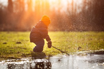 Little boy playing in puddle at springtime