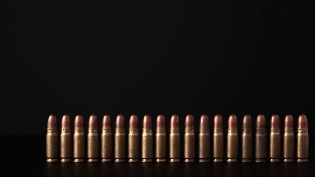 Hand of man removes the bullet turns standing in a row on a dark background.
