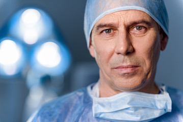 Serious doctor standing in operating room