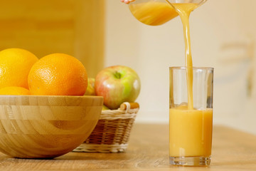 Pouring orange juice from glass carafe, on wooden table