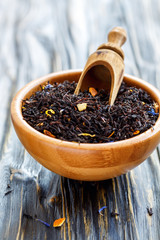 Tea with bergamot and flower petals in a wooden bowl.