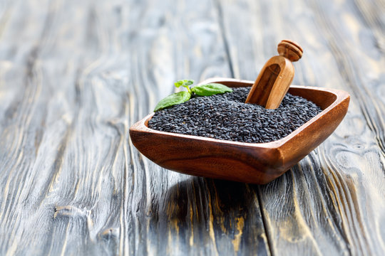 Black sesame seeds in a wooden bowl.