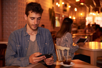 Cute millennial looking at his cellphone