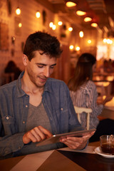 Smiling young man typing on tablet
