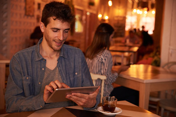Happily typing young man in restaurant