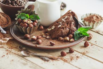Piece of chocolate cake, mint leaves, hazelnuts and jar with milk