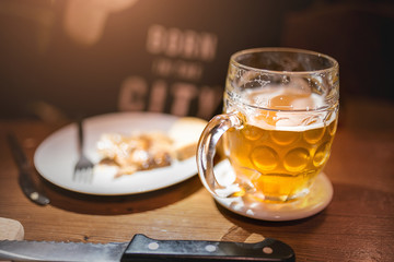 Glass of beer with snack food on a plate in Prague old pub