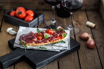 Traditional parma cured ham antipasto on wooden background, rustic style