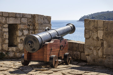 Fototapeta na wymiar Ancient iron cannon on wooden mount on Dubrovnik stone rampart