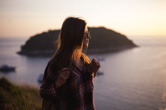 Young stylish hipster girl enjoy sunset on viewpoint. Travel woman with backpack