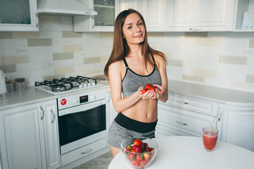 Girl drinking strawberry smoothie on the kitchen.