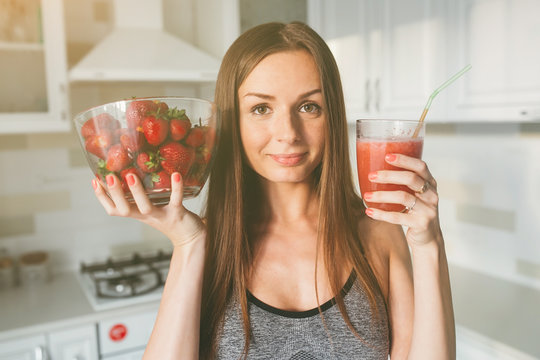 Girl drinking strawberry smoothie on the kitchen.