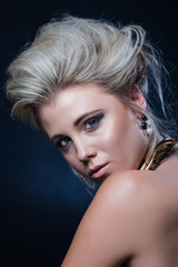 Beautiful blond female fashion model photographed in a dark studio