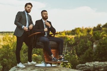 Naklejka na ściany i meble Handsome professional barbers posing together outdoors on the edge of a canyon