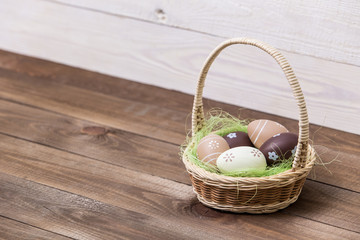 Fototapeta na wymiar Happy easter! Beautiful Easter eggs are decorated in bed colors in a basket on a wooden background. Easter conceptual background