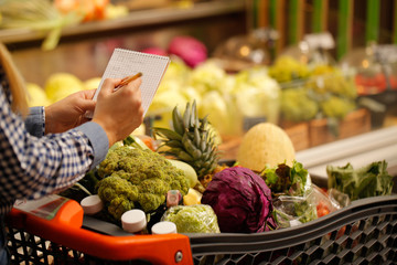 Happy couple with a shopping list at the groceries store