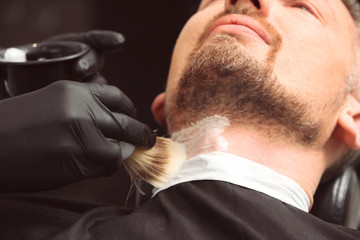 Hairdresser shaving client in barbershop