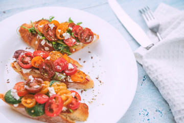 Bruschetta with cheese, basil, arugula and cherry tomatoes