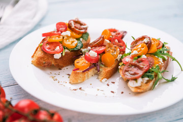 Bruschetta with cheese, basil, arugula and cherry tomatoes