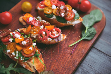 Bruschetta with cheese, basil, arugula and cherry tomatoes