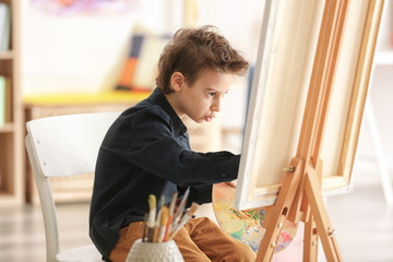 Cute little artist painting picture in studio