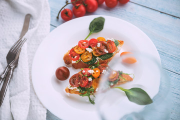 Bruschetta with cheese, basil, arugula and cherry tomatoes and a glass of white wine
