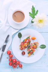 Bruschetta with cheese, basil, arugula and cherry tomatoes and a glass of white wine