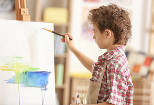 Cute little artist painting picture in studio