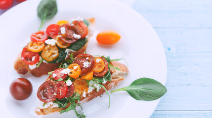 Bruschetta with cheese, basil, arugula and cherry tomatoes and a glass of white wine
