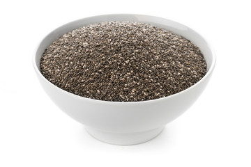 Raw, unprocessed, dried black chia seeds in white bowl on white