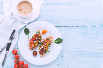Bruschetta with cheese, basil, arugula and cherry tomatoes and a glass of white wine