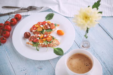 Bruschetta with cheese, basil, arugula and cherry tomatoes and a glass of white wine