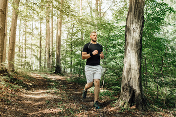 Male runner running along a nature trail through the woods