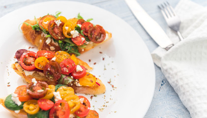 Bruschetta with cheese, basil, arugula and cherry tomatoes